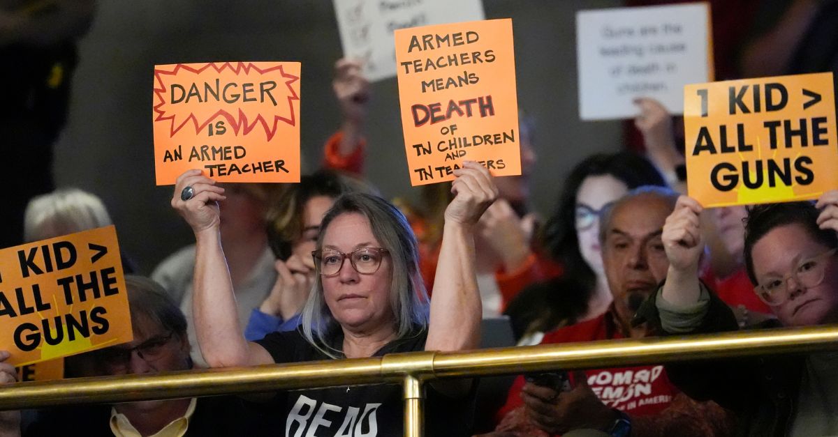 People hold signs in the gallery against a bill that would allow some teachers to be armed in schools during a legislative session in the House chamber Tuesday, April 23, 2024, in Nashville, Tenn. (AP Photo/George Walker IV)